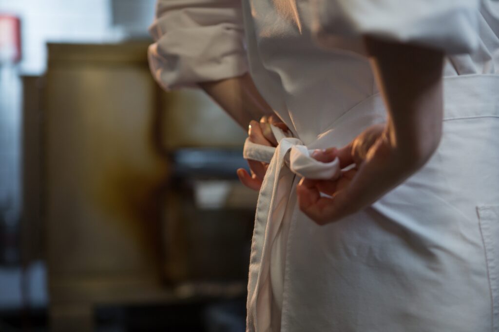 A chef ties the strings of her apron before the start of a shift